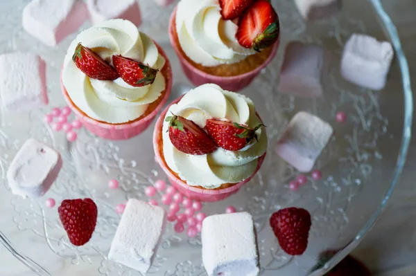 Cupcakes cu frisca si crema dulce, decorate cu capsuni. Pe un suport de sticlă, cu bezele — Fotografie, imagine de stoc