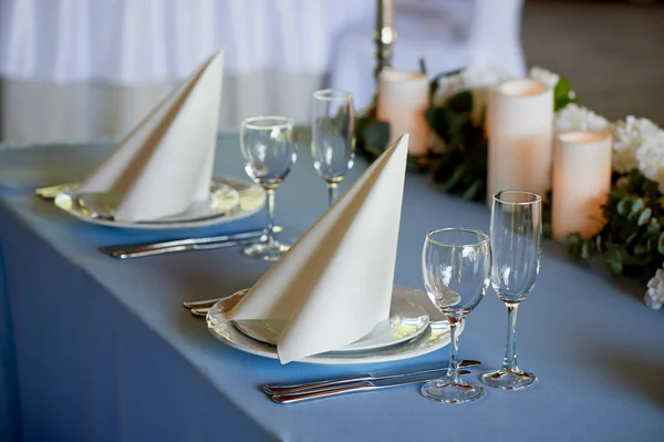 Подавать свадебный стол. Украшенные белые салфетки, свечи и цветы на голубой скатерти. Таблица молодоженов — стоковое фото