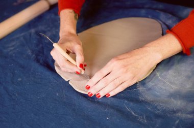 Yaratıcı atölye ustası. Bir toprak çanak formu oluşturma neşterle kırpma. İş akışı