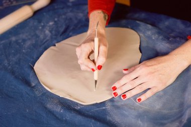 Yaratıcı atölye ustası. Bir toprak çanak formu oluşturma neşterle kırpma. İş akışı