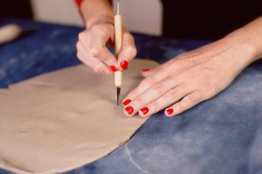 Yaratıcı atölye ustası. Bir toprak çanak formu oluşturma neşterle kırpma. İş akışı