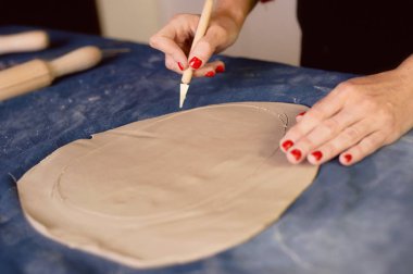 Yaratıcı atölye ustası. Bir toprak çanak formu oluşturma neşterle kırpma. İş akışı