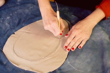 Yaratıcı atölye ustası. Bir toprak çanak formu oluşturma neşterle kırpma. İş akışı