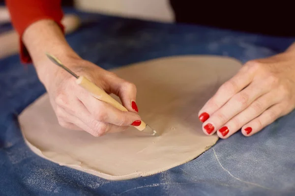 Oficina criativa de cerâmica. Aparar com um bisturi, criando a forma de um prato de barra.Fluxo de trabalho — Fotografia de Stock