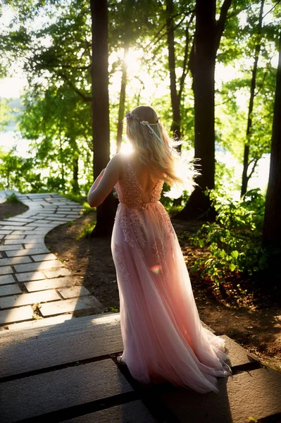 Batan güneşin dantel ile şeftali elbiseli gelinin güzel ormanda dönen siluet. İyi bir rakam ile sarışın. Mutluluk ve huzur hissi — Stok fotoğraf