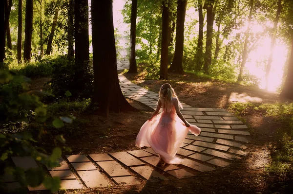 Batan güneşin dantel ile şeftali elbiseli gelinin güzel ormanda dönen siluet. İyi bir rakam ile sarışın. Mutluluk ve huzur hissi