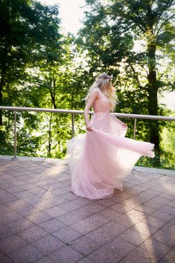 Batan güneşin dantel ile şeftali elbiseli gelinin güzel ormanda dönen siluet. İyi bir rakam ile sarışın. Mutluluk ve huzur hissi