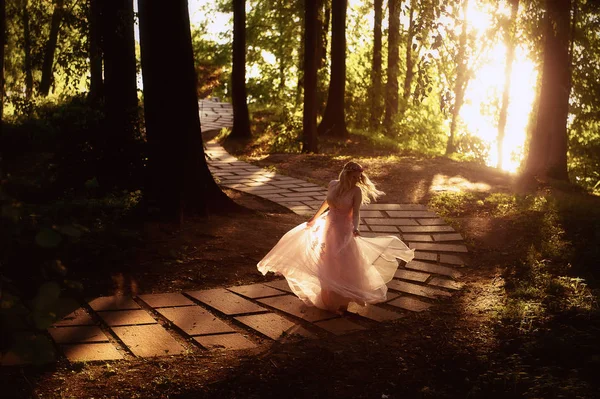 Silhouette vorticosa al sole al tramonto nei bellissimi boschi della sposa in abito pesca con laco.Bionda con una buona figura.La sensazione di felicità e serenità — Foto Stock