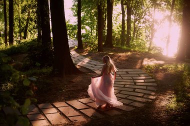 Batan güneşin dantel ile şeftali elbiseli gelinin güzel ormanda dönen siluet. İyi bir rakam ile sarışın. Mutluluk ve huzur hissi