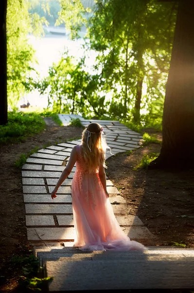 Silhouet wervelende in de ondergaande zon in de mooie bossen van de bruid in de perzik jurk met kant. Blonde met een goed figuur. Het gevoel van geluk en serenity — Stockfoto