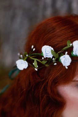 Güzel kızıl saçlı gelin geri oturur. Biraz görünür profil. El yapımı takı ile uzun kıvırcık saç.