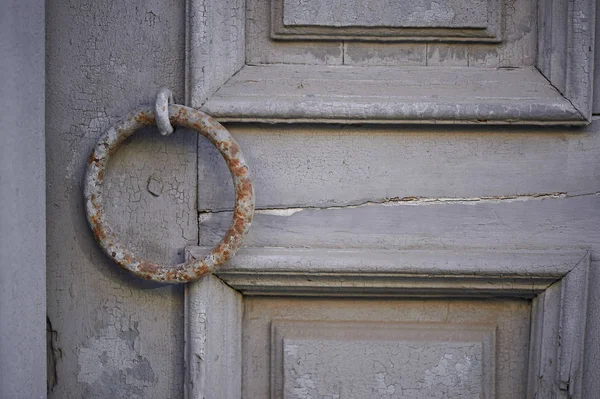 Vecchia porta grigia vintage con vernice peeling e una maniglia arrugginita a forma di anello . — Foto Stock