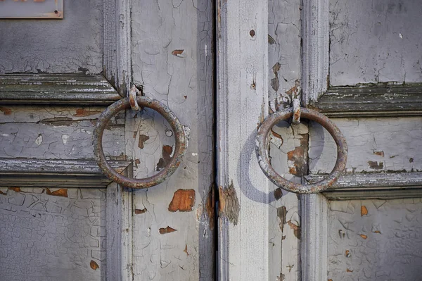 Oude vintage grijs deur met verf en een roestig handvat in de vorm van een ring peeling. — Stockfoto