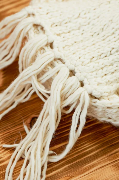 Bufanda blanca cálida de punto grueso mantener en la superficie de madera.Macro. El ambiente es cálido y el otoño —  Fotos de Stock