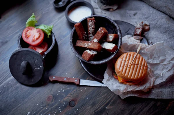 Burger with garlic croutons in the dark interior of the pub. Hearty, quick lunch.Atmospheric photo — Stock Photo, Image