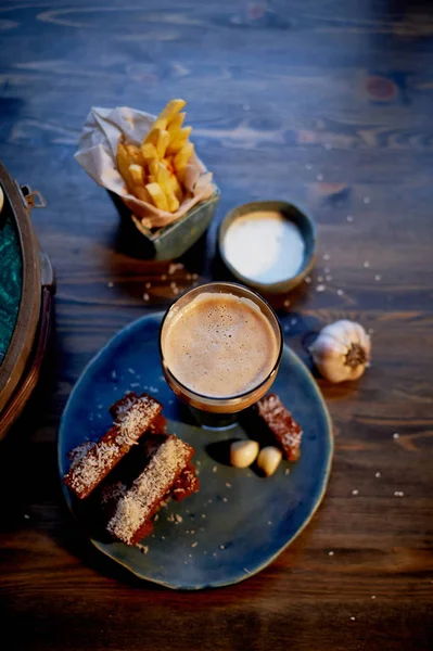 The atmosphere of the old cafe.The player with the disc, a glass of dark beer, garlic bread and fries. Fast food — Stock Photo, Image