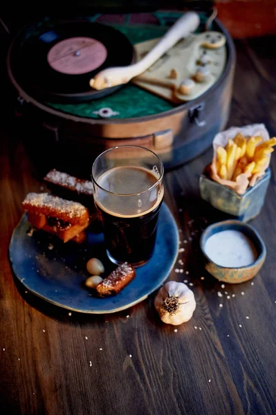 The atmosphere of the old cafe.The player with the disc, a glass of dark beer, garlic bread and fries. Fast food — Stock Photo, Image