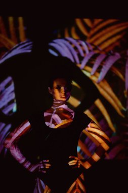 Soyut portre projektör ışığında güzel bir kız. Mor ve turuncu renkler. Uzaylı orman. Güzel, tehlikeli ve gizemli