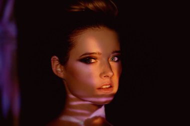 Soyut portre projektör ışığında güzel bir kız. Mor ve turuncu renkler. Uzaylı orman. Güzel, tehlikeli ve gizemli