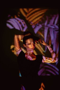 Soyut portre projektör ışığında güzel bir kız. Mor ve turuncu renkler. Uzaylı orman. Güzel, tehlikeli ve gizemli