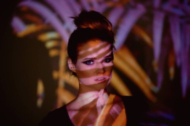 Soyut portre projektör ışığında güzel bir kız. Mor ve turuncu renkler. Uzaylı orman. Güzel, tehlikeli ve gizemli