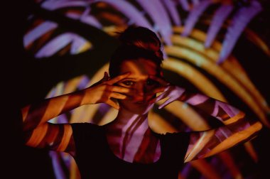 Soyut portre projektör ışığında güzel bir kız. Mor ve turuncu renkler. Uzaylı orman. Güzel, tehlikeli ve gizemli