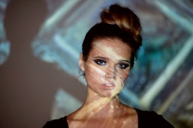 Soyut portre projektör ışığında güzel bir kız. Serin gölgeler. Güzel ve gizemli. Topuz tarzı saç.