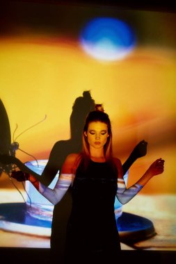 Soyut portre projektör ışığında güzel bir kız. Sıcak turuncu tonları. Siyah kelebek resmi. Kırılganlık ve güzellik duygusu. Plastik gövdeli. Güzel ve gizemli. Topuz