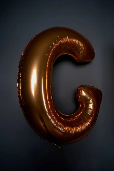 Golden balloons in the form of letters. The letter C. the Atmosphere of celebration, bachelorette party