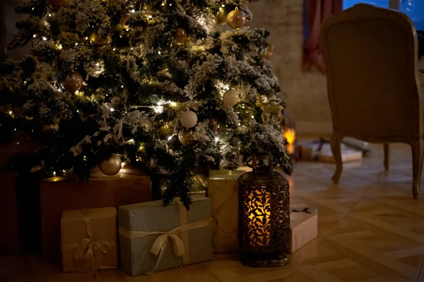 Gezellige kerstboom met kerstverlichting en dozen van presenteert. Warme kleuren, intieme twilight — Stockfoto