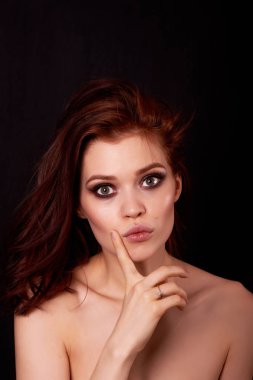 Siyah bir arka plan güzel kızıl saçlı kız. Sürpriz ve soru gözünde. Parmak yüz yakın. Duygular