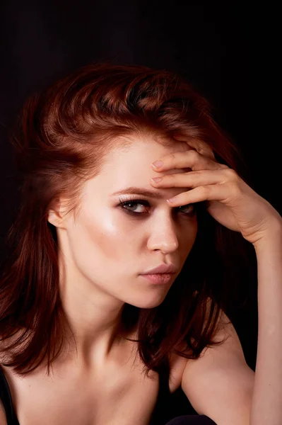 Κορίτσι στο Studio σε σκούρο φόντο. Κόκκινα μαλλιά, μεγάλο σχήμα. Μυστηριώδης, χέρια σταυρωμένα γύρω από τα χείλη. Ο σκεπτικός ματιά — Φωτογραφία Αρχείου