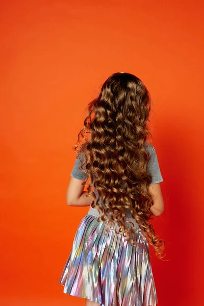 Chica sobre fondo naranja en el Estudio. Cabello rizado muy largo como en un cuento de hadas. — Foto de Stock