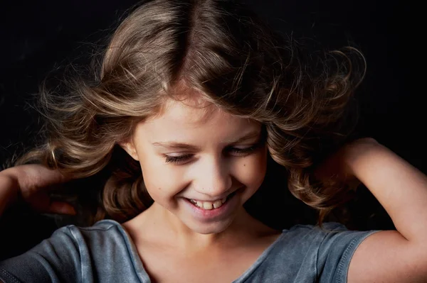 Chica rizada con el pelo largo. En el estudio sobre un fondo negro. Un cuento de hadas para niños.Vive en el marco —  Fotos de Stock