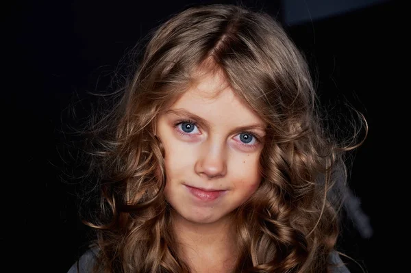 Chica rizada con el pelo largo. En el estudio sobre un fondo negro. Un cuento de hadas para niños.Vive en el marco — Foto de Stock