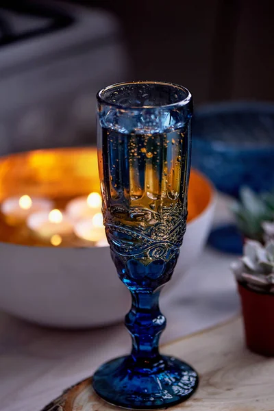 Un vaso de vino o agua de un vaso azul.Luz cálida de velas. Cena romántica —  Fotos de Stock