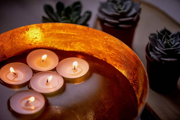 Cuenco dorado con agua en el que flotan las velas. Decoración interior para un ambiente relajado —  Fotos de Stock