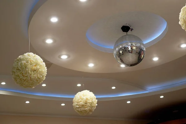 The high white ceiling with exposed beams. Decorated with disco balls.With the backlight. Night life