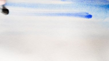 Sanatçı mavi suluboya boya ile kalın kağıdın ıslak kapsar. Arka plan, çok yakın