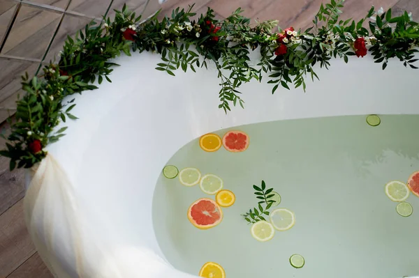 Água de leite no banho, que nadam citrinos: limão, limão e toranja. Cuidados com a pele e relaxamento Banho cheio de água e decorado com flores — Fotografia de Stock