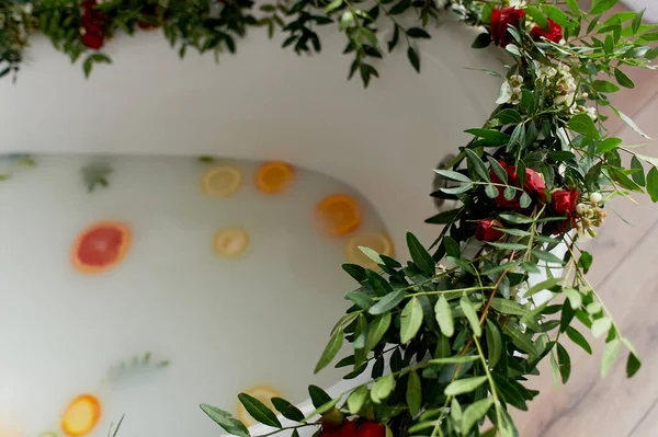 Água de leite no banho, que nadam citrinos: limão, limão e toranja. Cuidados com a pele e relaxamento Banho cheio de água e decorado com flores — Fotografia de Stock