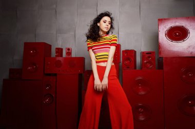 Studio moda çekim. Kız parlak bir kıyafet, üst ve altına kırmızı ve turuncu renklerde alevlendi. Esmer kıvırcık saçlı dans