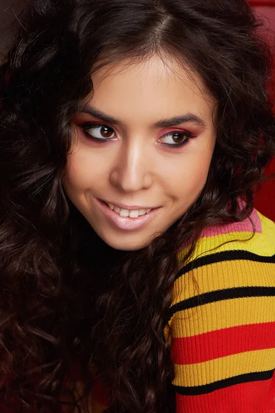 Estúdio de moda. A menina em uma roupa brilhante, top e calças brilhou em cores vermelhas e laranja. Morena com cabelo encaracolado. Retrato de close-up. Olho castanho — Fotografia de Stock