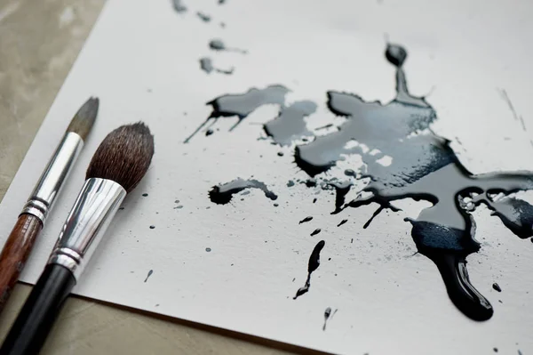 Blatt weißes Papier mit schwarzen, mit Tinte gefertigten Kunstflecken. — Stockfoto