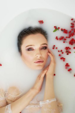 Parlak Studio.Delicate ve barış ve huzur şehvetli atmosferini. Dolgun dudaklar, zarif ince bilek, güzel bir kızla Relaxation.Portrait saç ıslak. Rowan ile süt banyosu içinde yatan.