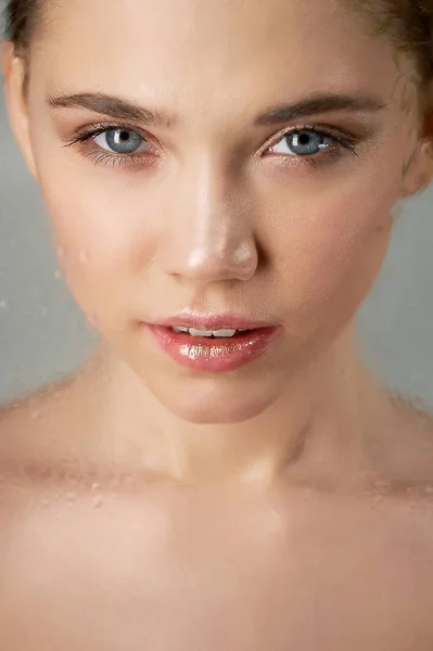 Portrait de jeune belle fille en studio, avec maquillage professionnel.Tournage de beauté. Face à un verre transparent avec des gouttelettes d'eau. Hydratation de la peau — Photo