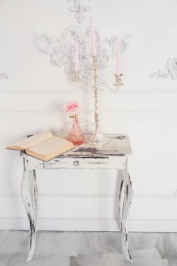 Retro Ahşap Masa oyma legs, bir kitap, bir avize pembe mum ile. Antik, entelektüel cazibe atmosferini
