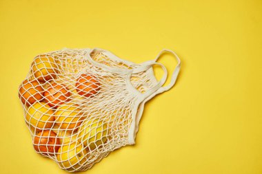 Plastik poşetler değiştiriliyor. Çevreyle ilgilenmek. Renkli kâğıt üzerinde meyveli şebeke, takviye. Minimalizm.