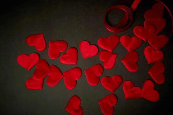 Valentines day,a Declaration of love. A lot of red hearts on a dark gray background, and a red ribbon.