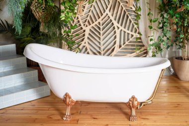 Bir sürü yeşil bitkisi olan Asya tarzı bir küvet. Pençelerinde beyaz bir küvet..